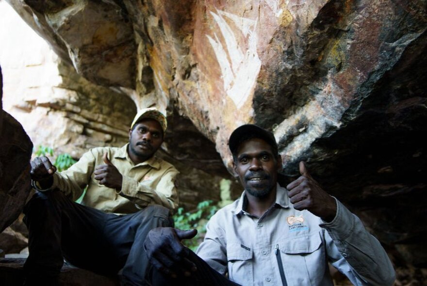 Two Indigenous guides on a rock art tour in a sandstone rock shelter.