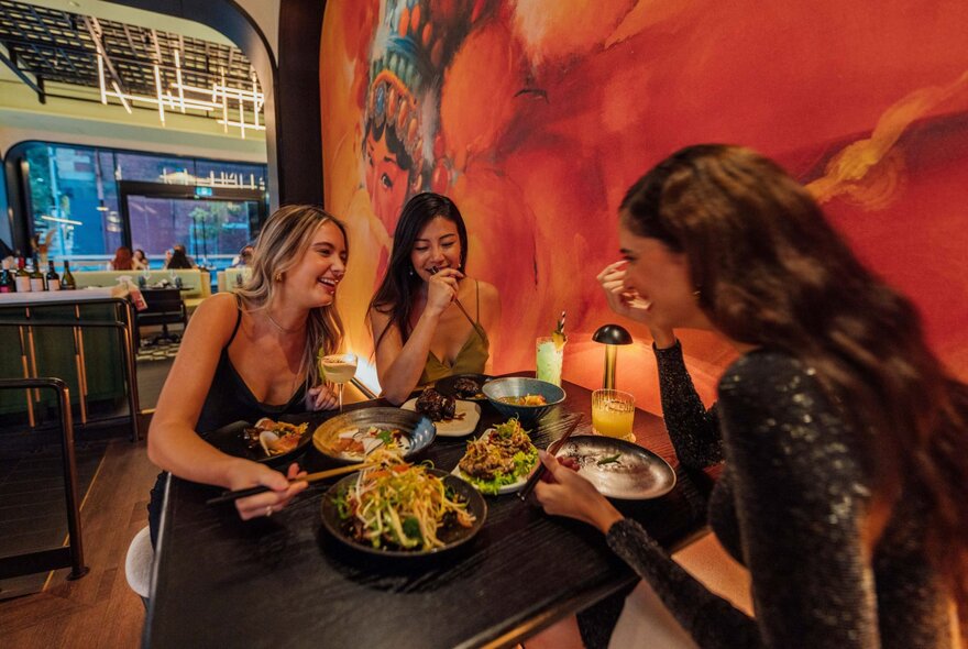Three friends eating a meal together at a table inside Miss Mi restaurant.