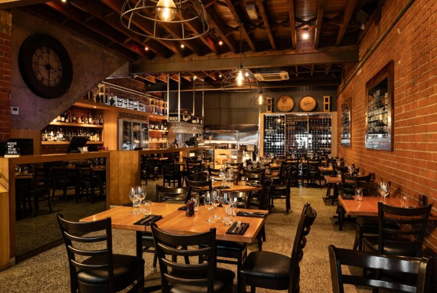 An empty restaurant in dark wood tones with beams on the ceiling. 