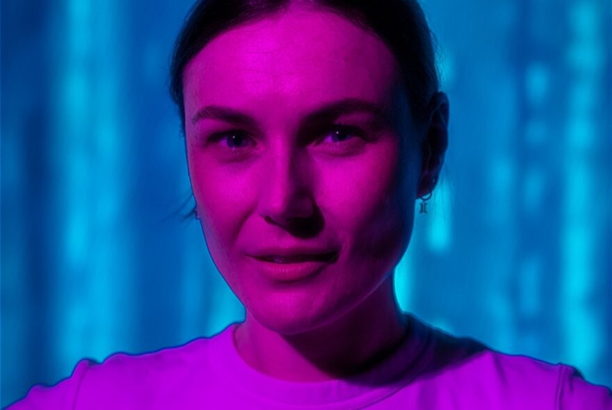 Woman's head with purple lighting against a blue background.