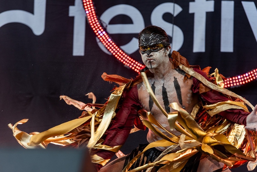 A male dancer dressed in a flame-like costume, on stage.