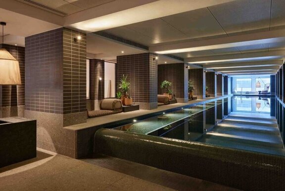 The indoor pool at Hyatt Centric hotel with lounging areas and potted plants.