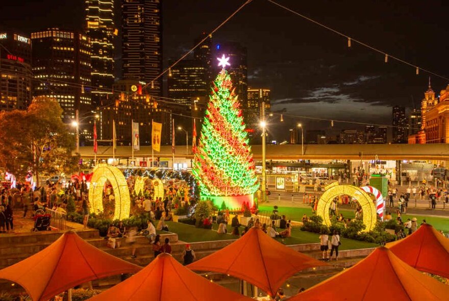 A giant glowing Christmas tree in the middle of a city square.