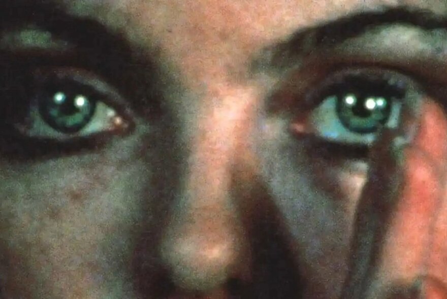 A close up of a woman's face with her fingers in front of one eye.
