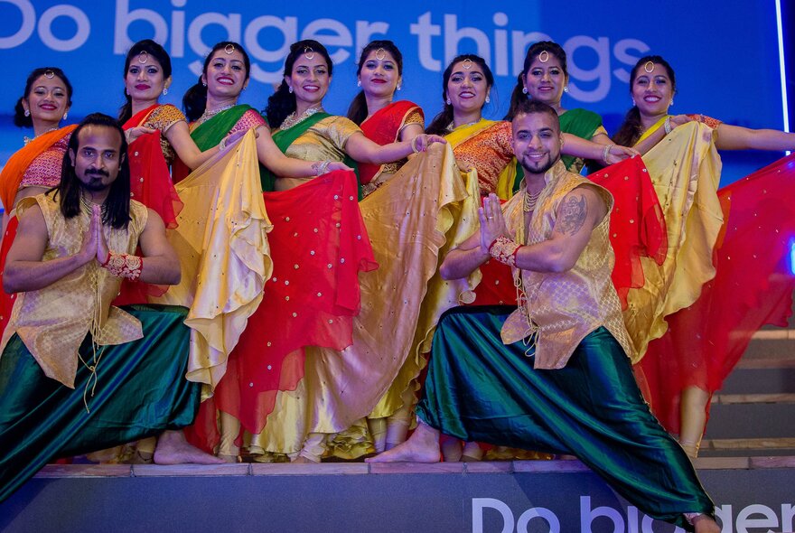 Sri Lankan dancers in colourful traditional costumes posing on stage.