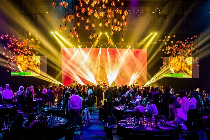 Interior space of Melbourne Convention and Exhibition Centre showing tables and stage lighting.