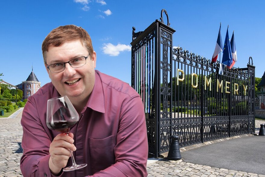 Sommelier Antony holding a glass of wine in front of winemaker Pommery's gates in France.