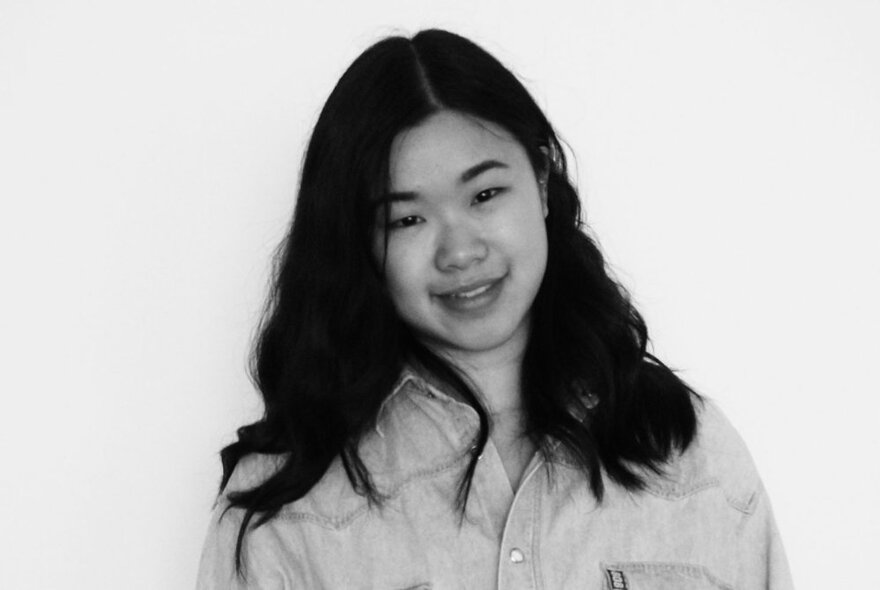 A black and white portrait of a young Asian woman with her hair down around her shoulders, wearing a shirt.