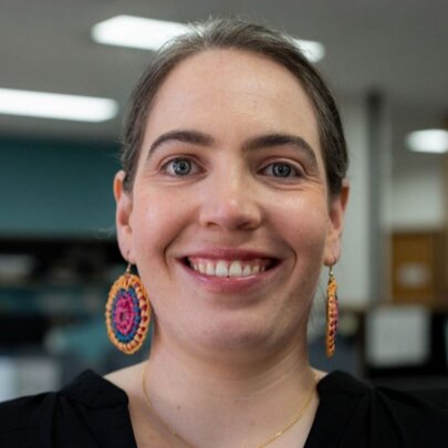 A woman with large tribal earrings smiling warmly in an office. 