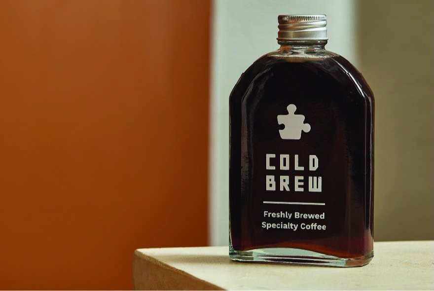 A thin bottle of cold brew coffee on a white counter.