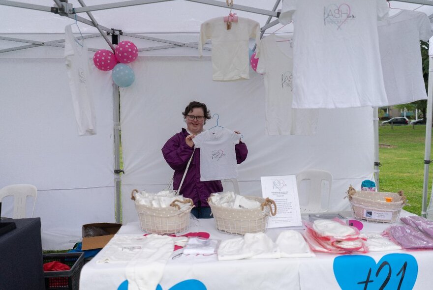 A person at a charity stall selling T-shirts and other clothing.