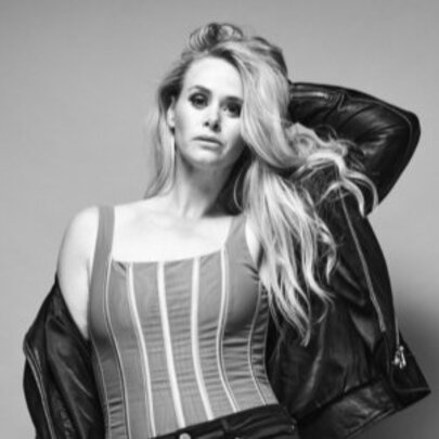 Australian singer Kate DeAraugo in a textured striped top paired with a draped black jacket, posed against a pale background; a black and white image.