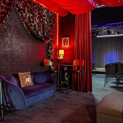 The lobby of a comedy venue, with a blue velvet couch and red curtains.