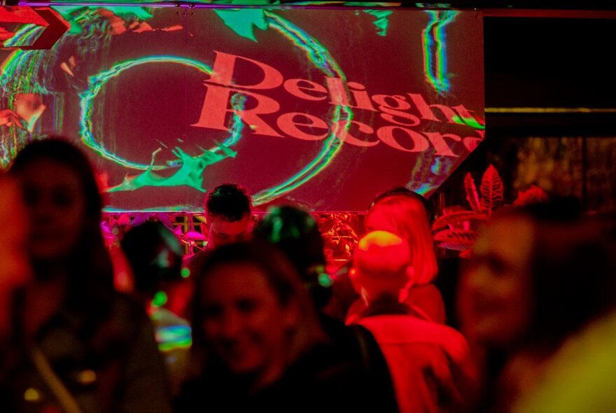 A crowded club with people dancing under lights that cast a red filter.