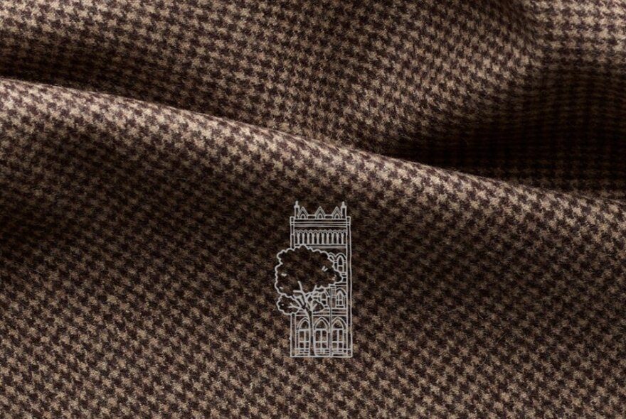 Close-up of houndstooth fabric with a ghosted out design of a terrace building and tree in the centre of the image.