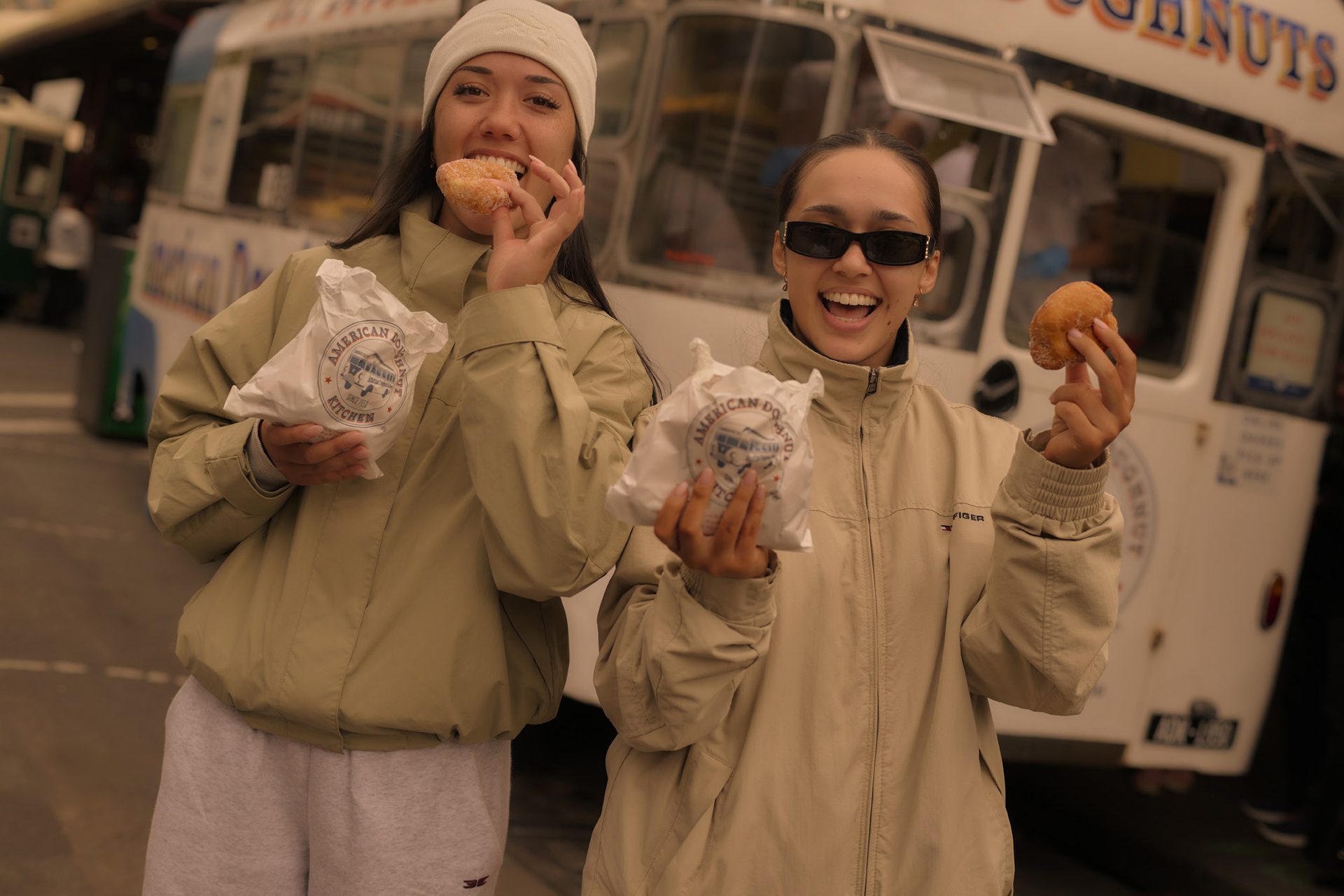 Two girls holding bags of cinnamon doughnuts. 
