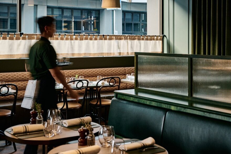 Restaurant interior with banquet and booth seating, cafe-style curtains and wait staff.