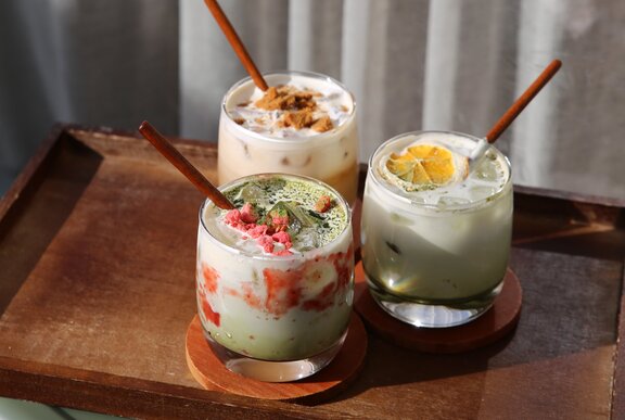 Three iced drinks on a wooden serving platter.