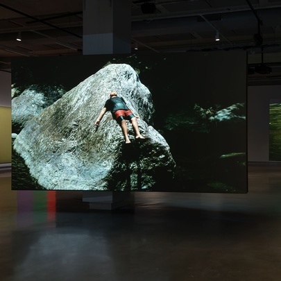 A large hanging piece of art showing a person lying back on a rock.