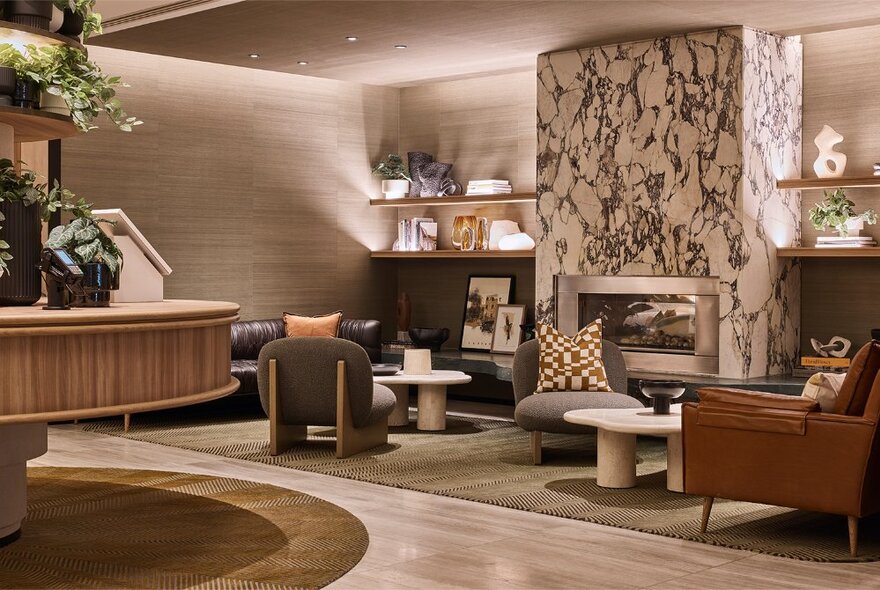 Hotel foyer with marble fireplace surrounded by low tables and seating.