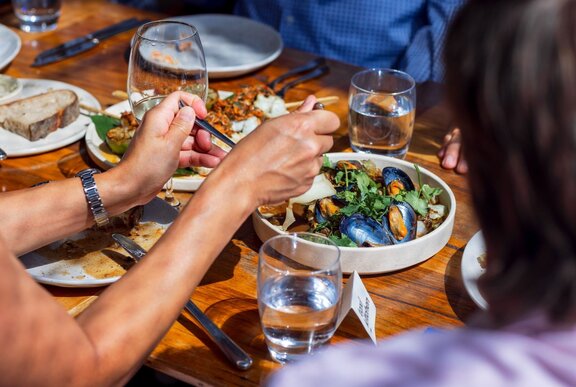 A person serving themselves from a share plate of salad at a restaurant.