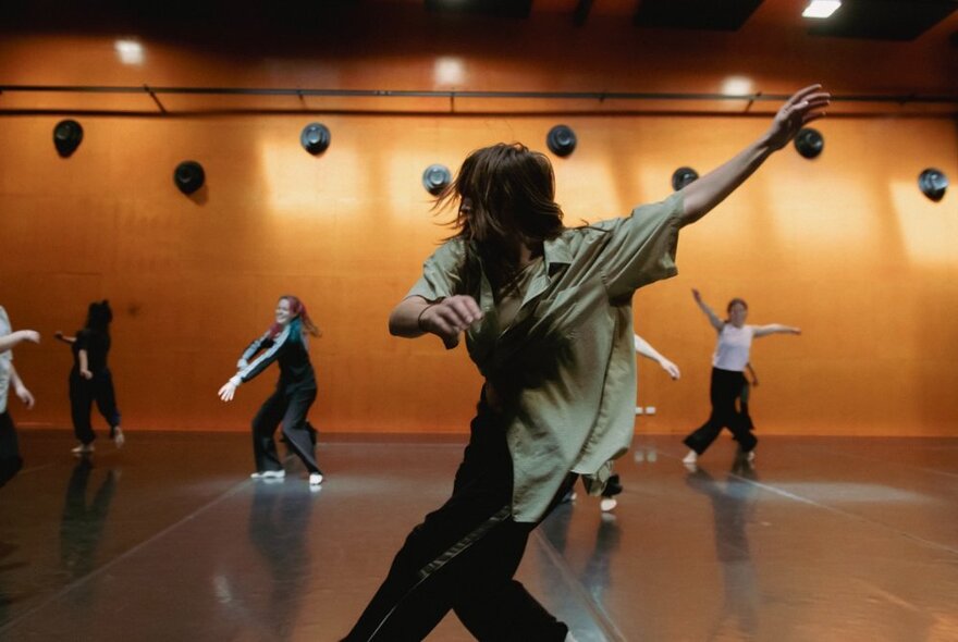 Dancers moving around freely in a large studio space.