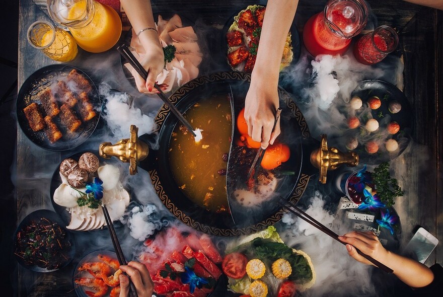 Sichuan hotpot ingredients being cooked at the table.