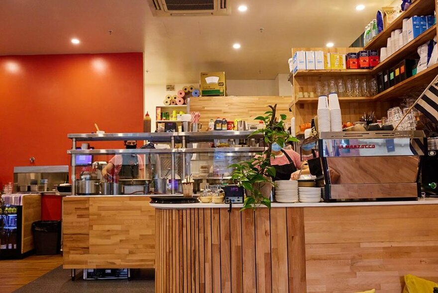 Coffee machine and a stainless display cabinet inside a cafe.