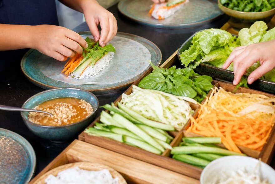 Children's hands arranging ingredients to make spring rolls.
