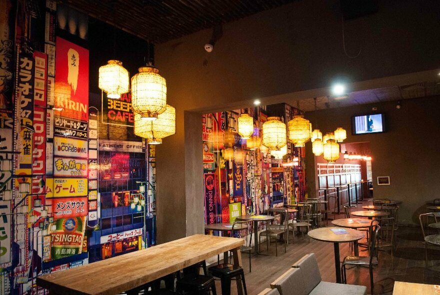 Tables and chairs in a bar setting with overhead lighting.