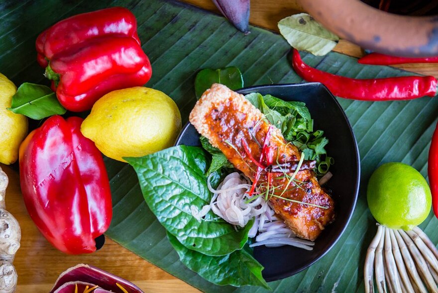 Looking down at a plate of Thai food with betel leaves, red capsicums, lemons and lime. 