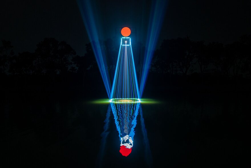 Blue laser beams with a red circle on top are reflected across the water’s surface.