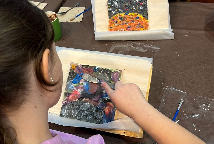 Looking over the shoulder of a child painting in chocolate