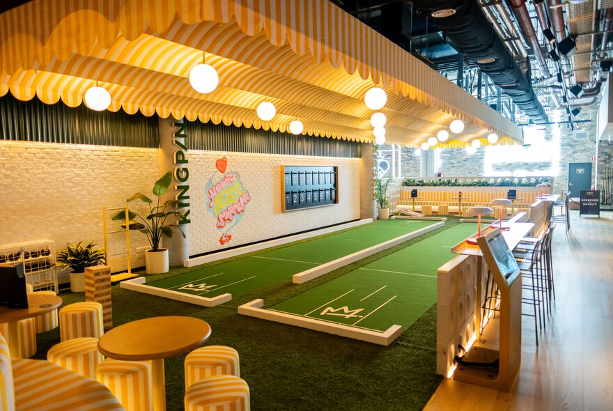 The indoor entertainment area at Kingpin Collins Street with a two dedicated green felt lawn bowls lanes and a seating area.