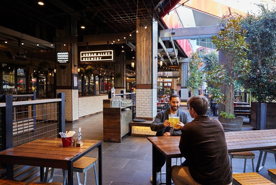 Two men drinking beer in a brewery beer garden. 