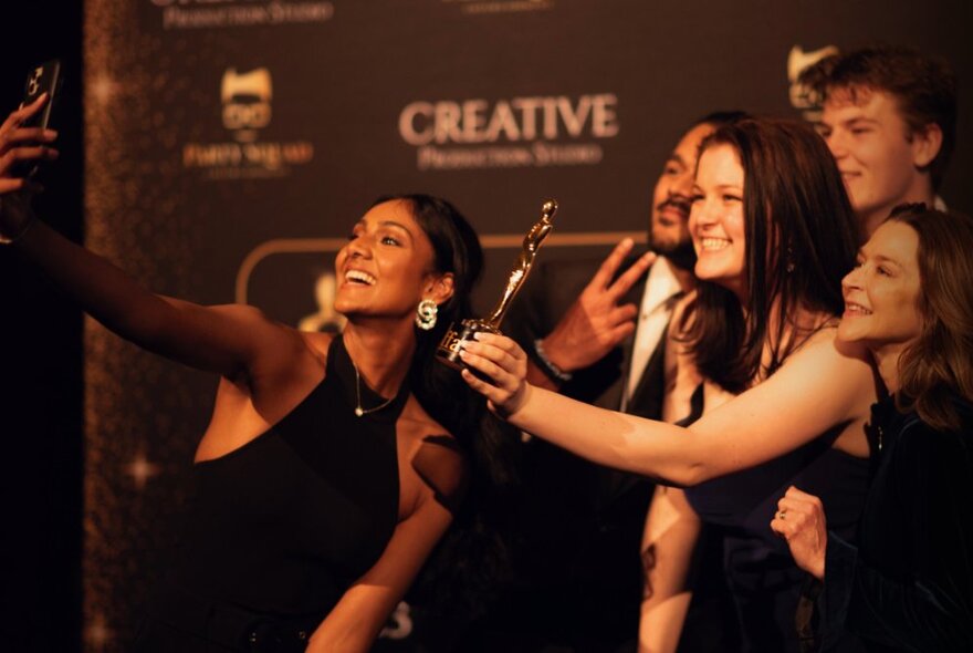 People taking a selfie with a gold IFFA award.