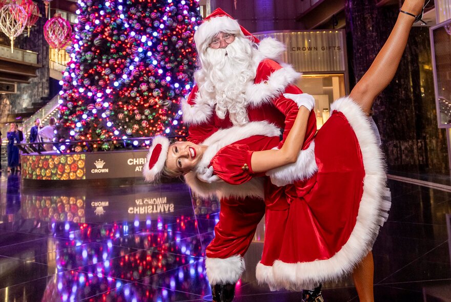 Santa and one of Santa's helpers posed in front of the Christmas tree at Crown Atrium.