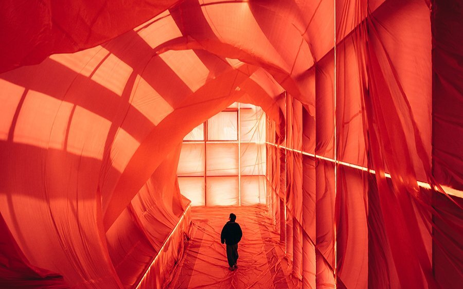 A person walking through a room draped in red fabric.