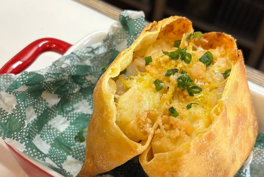 A lasagne pocket with a crispy outer shell and filling topped with chives.