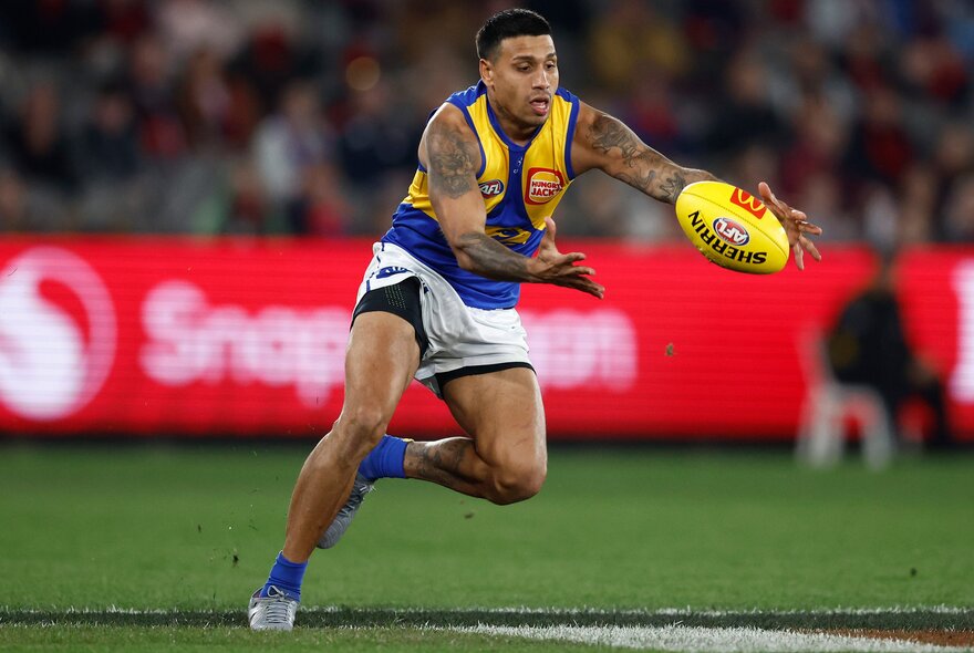 West Coast Eagle AFL football player catching a ball on the field during a match.