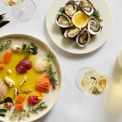A top-down view of a dining table with two plates of food and glasses of white wine.