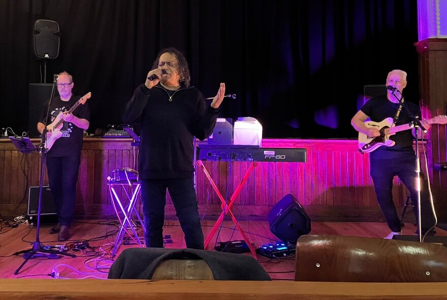 Soul musician Dinash Daniel playing with a band with pink. / purple stage lights. 