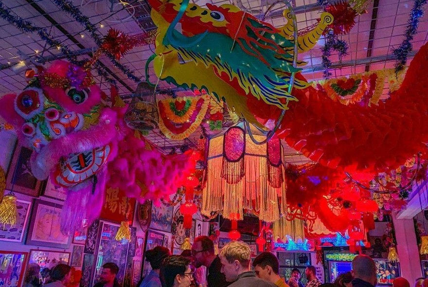 Interior of Heroes Bar showing brightly coloured ceiling and wall decorations over a crowd of heads.