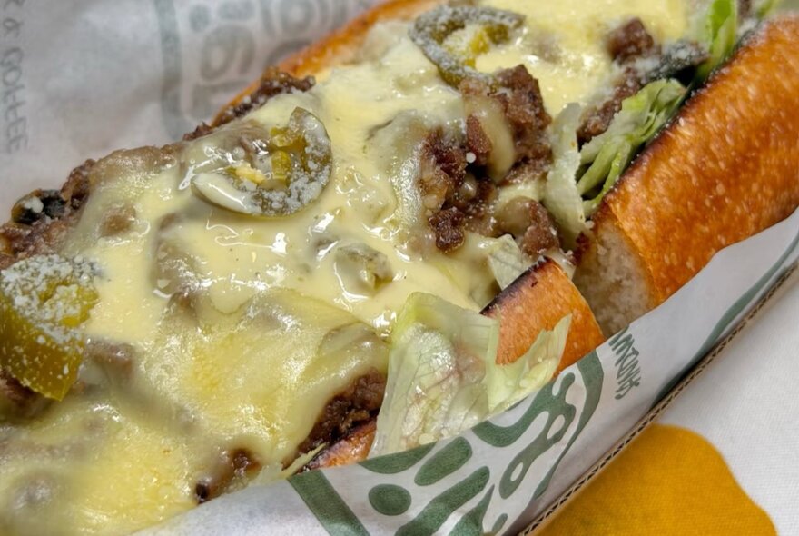 Melted cheese and beef sandwich in wrapper.