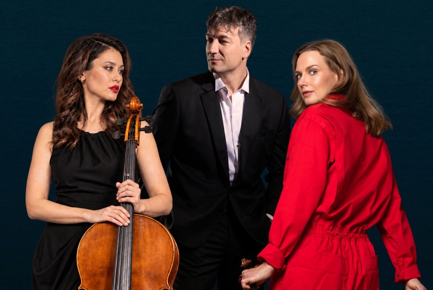 Three musicians, one holding a cello.
