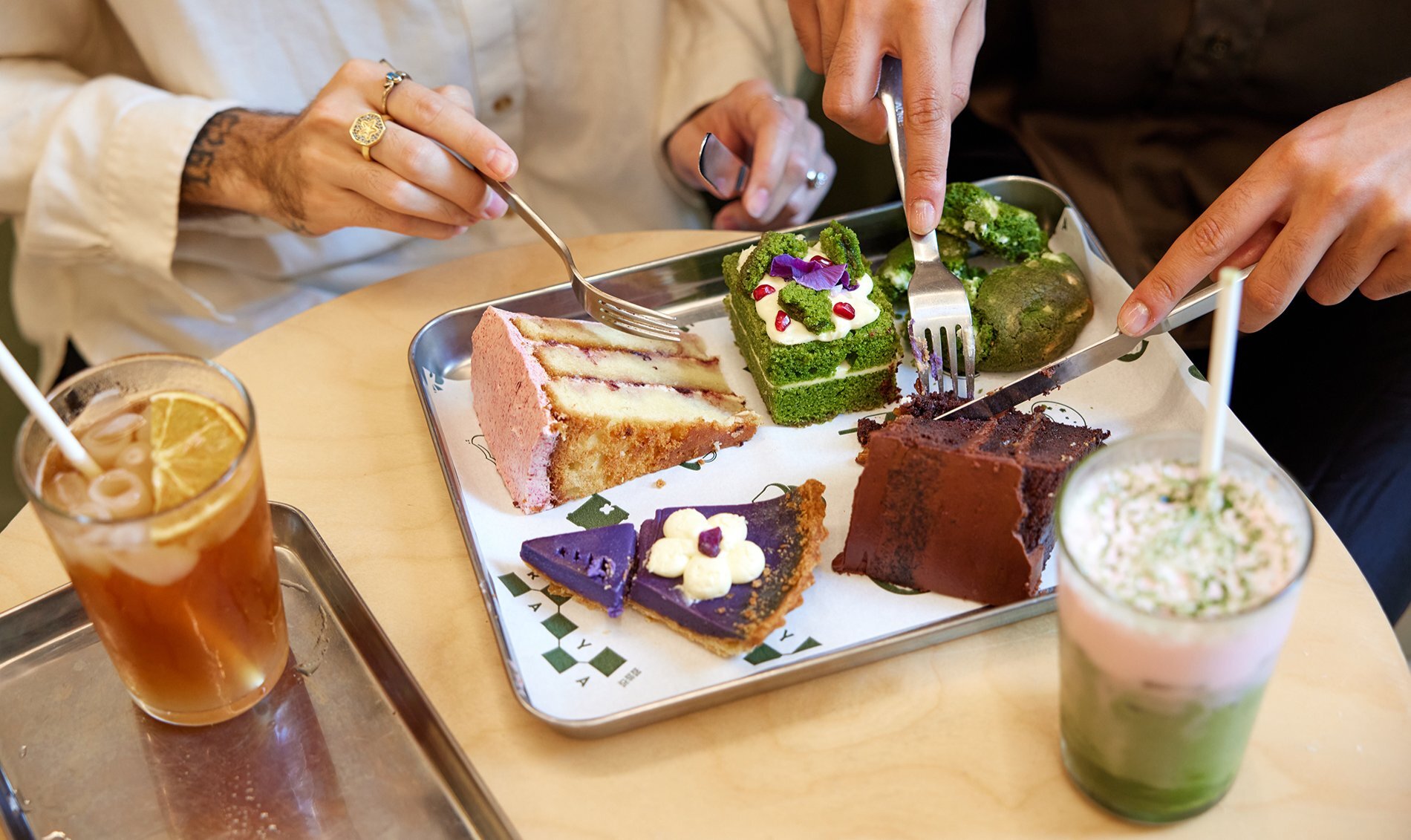 A silver tray of cakes next to two colourful drinks.