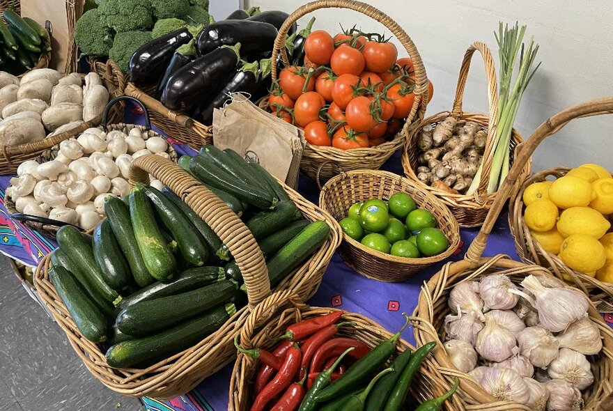 Baskets of fresh vegetables including zucchini, garlic, mushrooms, tomatoes and eggplant.