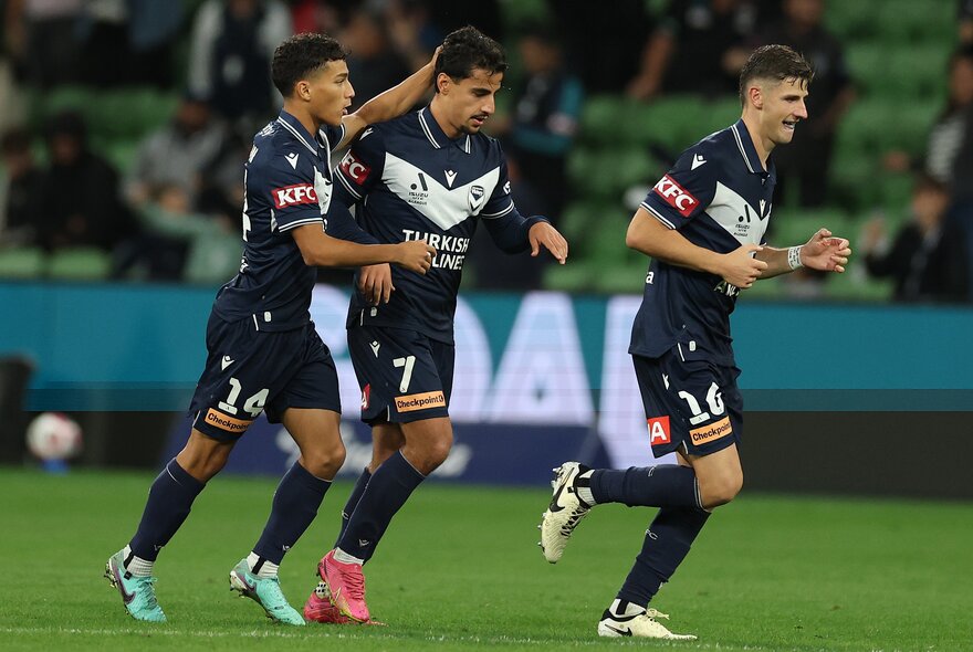 Soccer players on the field with a ball in the background.