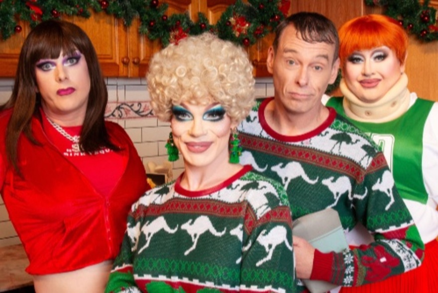 Four cast members from the musical 'A Fountain Lakes Christmas Carol: A Drag Parody Play', standing in a domestic kitchen dressed in festive-themed Australiana costumes.