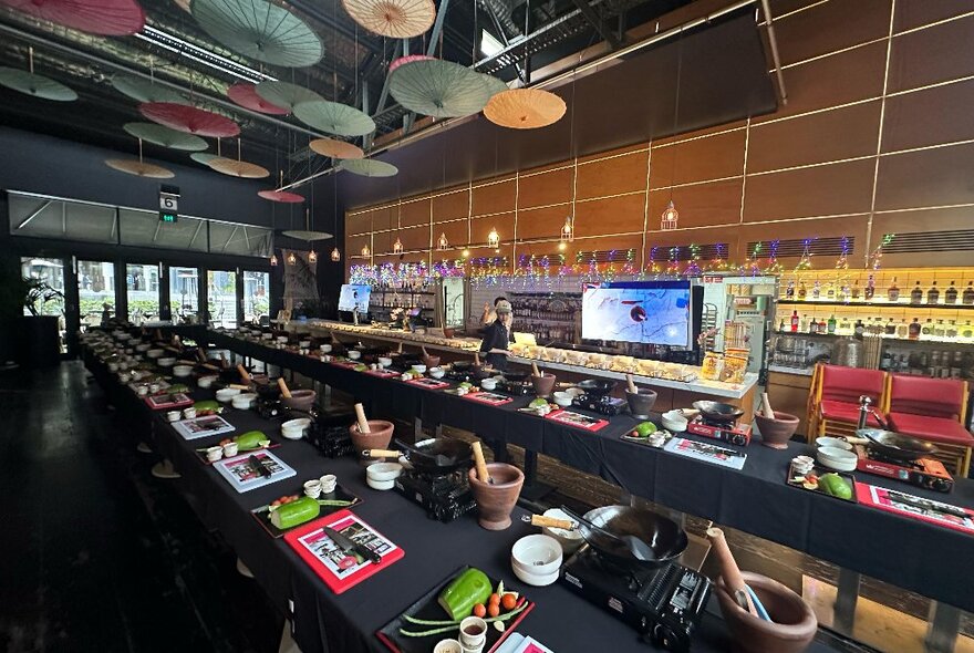 Long tables set up with cooking stations and ingredients, ready for a Thai cooking workshop.